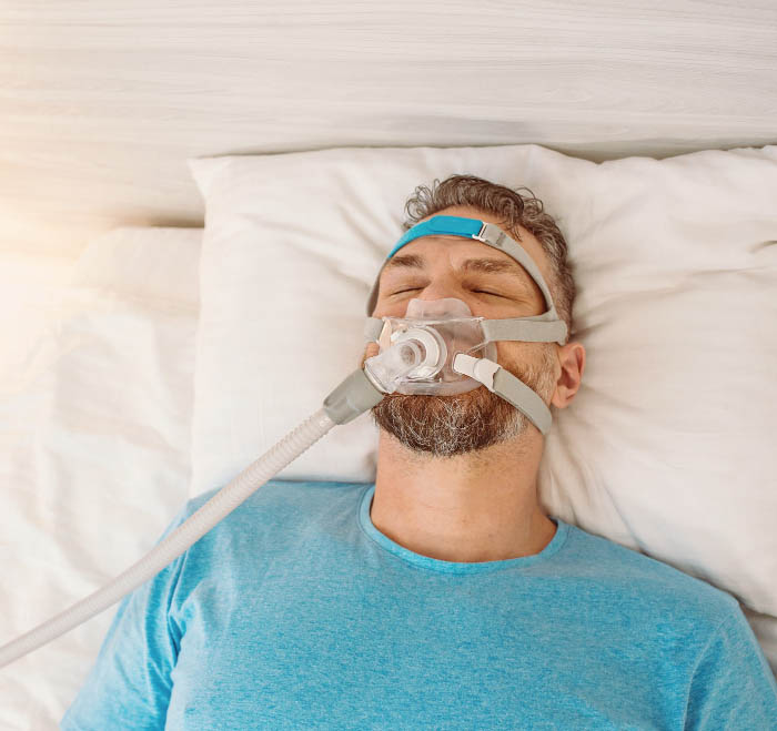 A man sleeping peacefully while wearing a CPAP mask for sleep apnea therapy.