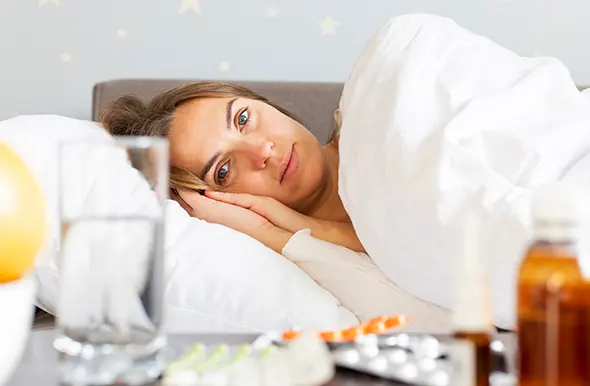 A male doctor in blue scrubs uses a stethoscope to examine a young girl's teddy bear.